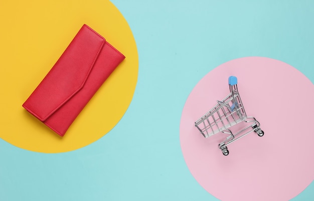 Shopping trolley, red leather wallet on color paper