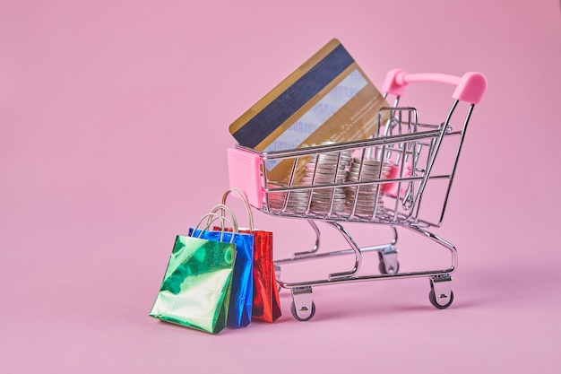 Carrello della spesa con carta di credito su uno sfondo rosa. idea creativa per lo shopping online.