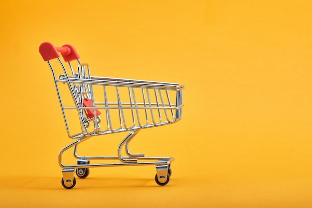 Shopping trolley on yellow background with some copy space