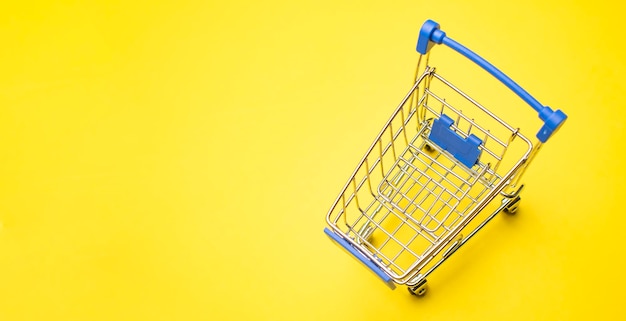 Shopping trolley on yellow background with some copy space