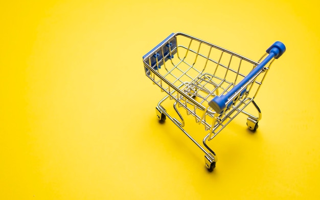 Shopping trolley on yellow background with some copy space