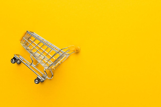 Shopping trolley on yellow background