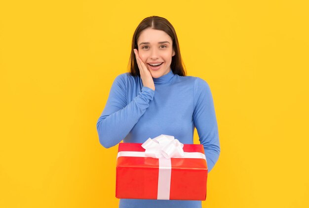 Shopping woman with purchase happy birthday holiday black friday discount seasonal sales surprised girl with box on yellow background boxing day present and gifts buy