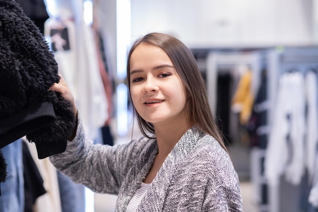 ショッピング若い女の子が店で服を選びます。