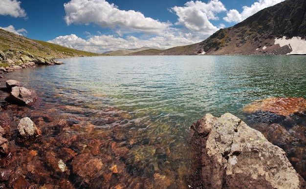 Sulla riva di un lago di montagna rocce sul fondo