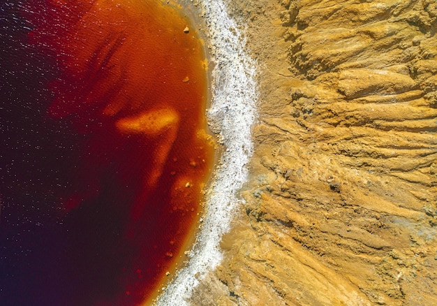 shore of toxic red lake in abandoned open pit copper mine