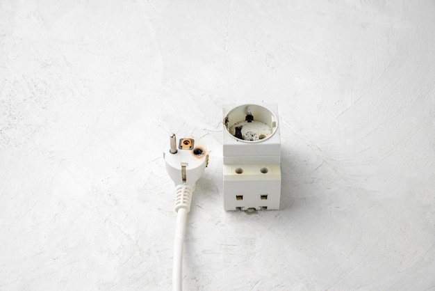 Photo short electrical circuit in the network burnt plug and socket closeup gray concrete background