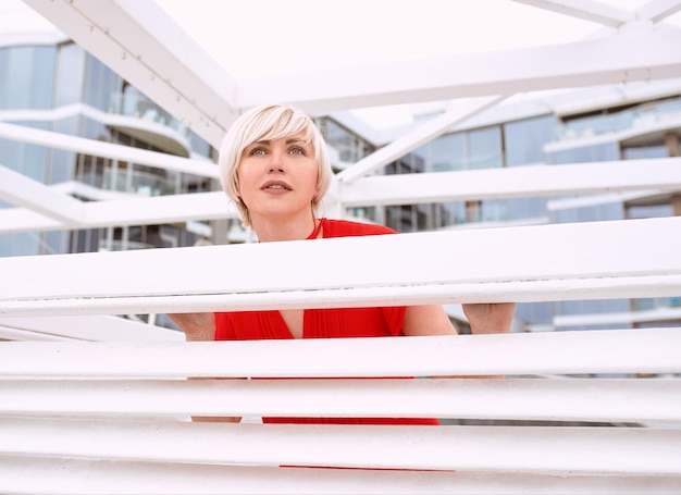 short hair blonde woman in red coral dress