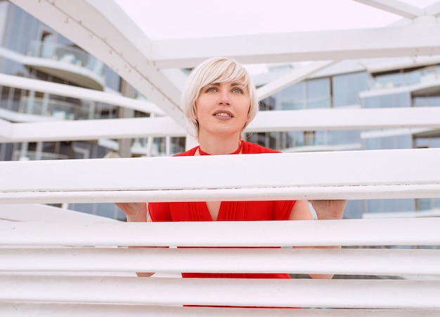 short hair blonde woman in red coral dress