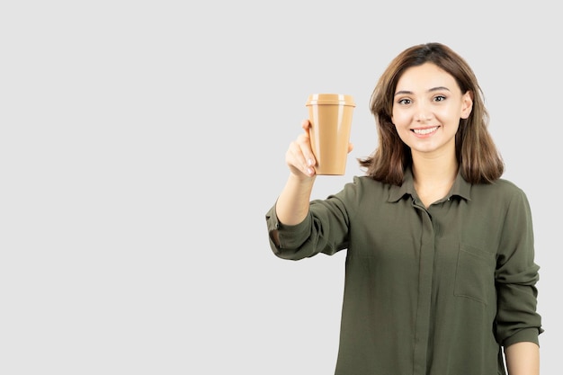 立って見ているコーヒーのカップを持つ短い髪の美しい少女。高品質の写真