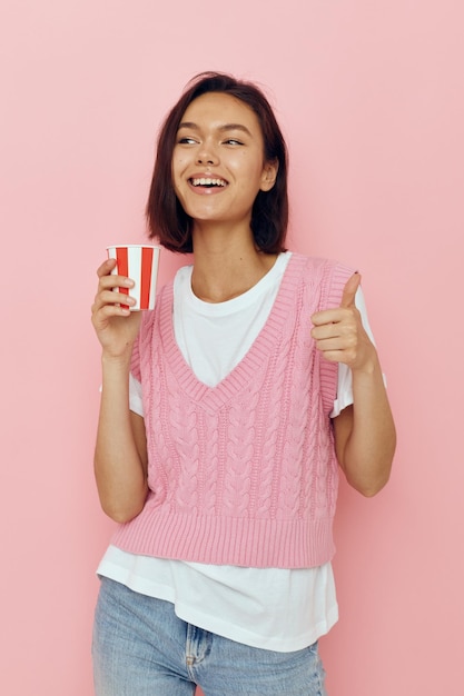 Short haired brunette with a glass in hand summer style pink t shirt isolated background