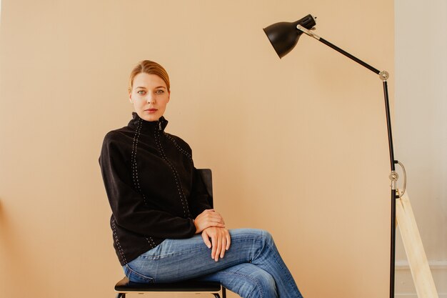 Short-haired woman in chair in front of studio light