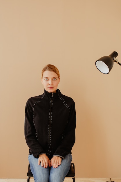 Short-haired woman in chair in front of studio light