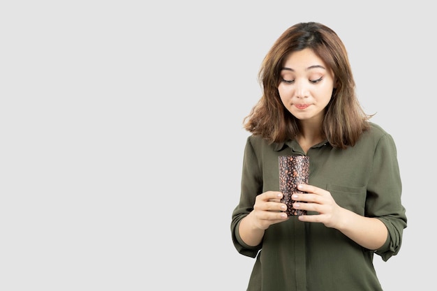 Short-haired young girl holding cup of latte over white wall. High quality photo