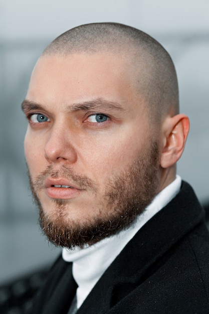 Short-haired young man in a black coat looks into the distance on the embankment in the bridge