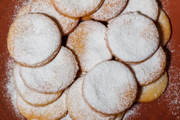 Short pastry cookies on red clay plate sprinkled with powdered sugar