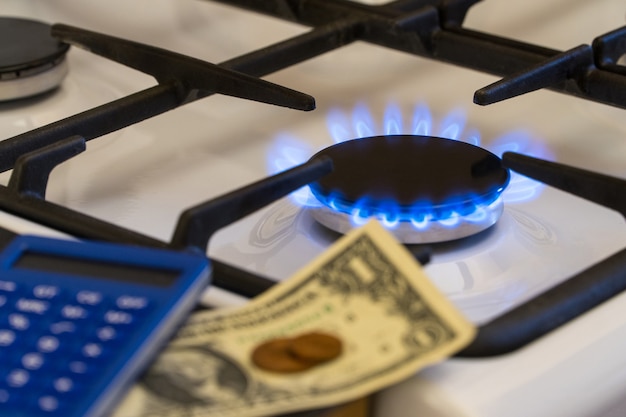 부족과 가스 위기. 불타는 가스 렌지의 배경에 돈과 계산기