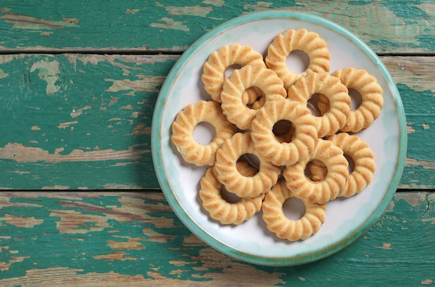 Shortbread cookies in plate on old green wooden background