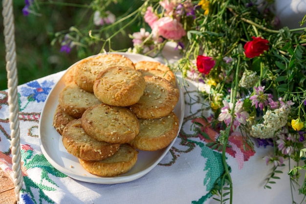 Biscotti di pasta frolla con formaggio blu e semi di sesamo e una ghirlanda di fiori di campo su un'altalena.
