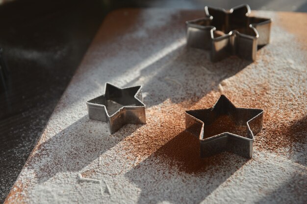 Shortbread dough for gingerbread cookies rolled on the wooden board. Cutting out star. New Year traditions concept and cooking process. Cookies on dark brown wooden table. Family making