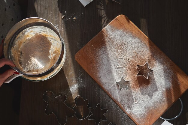 Shortbread dough for gingerbread cookies rolled on the wooden board. Cutting out star shaped cookies. 