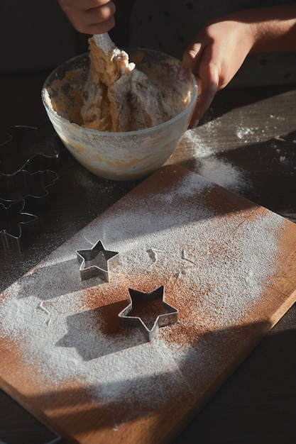 Shortbread dough for gingerbread cookies rolled on the wooden board. Cutting out star shaped cookies. 