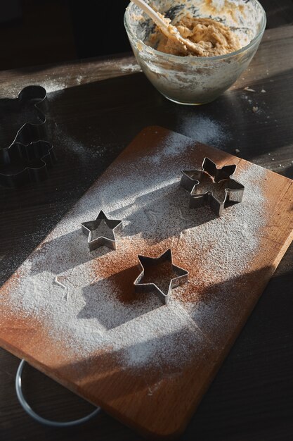 Shortbread dough for gingerbread cookies rolled on the wooden board. Cutting out star shaped cookies. 