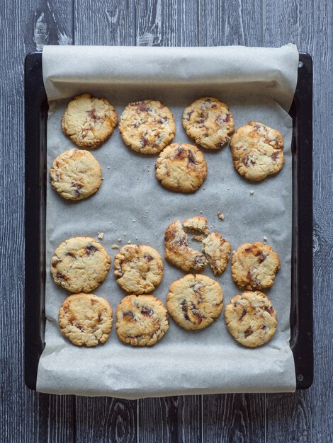 Shortbread with dates on a baking sheet is laid out on a dark wooden surface