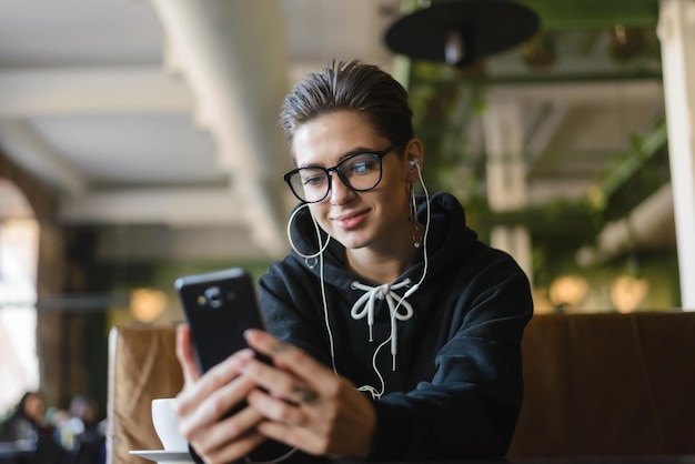 Shortcut hipster young woman searching music on internet websites for uploading in playlist on mobile phone