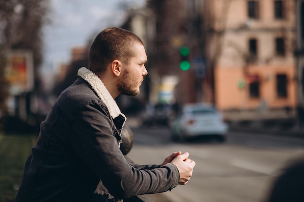 A shorthaired man is thoughtful and stands near the road looks into the distance expectation