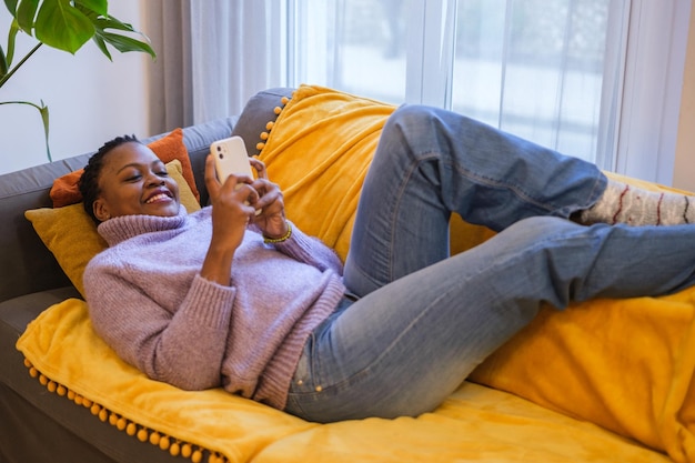 그녀의 스마트 폰을보고 집에서 휴식을 취하는 소파에 누워있는 Shorthaired 여자