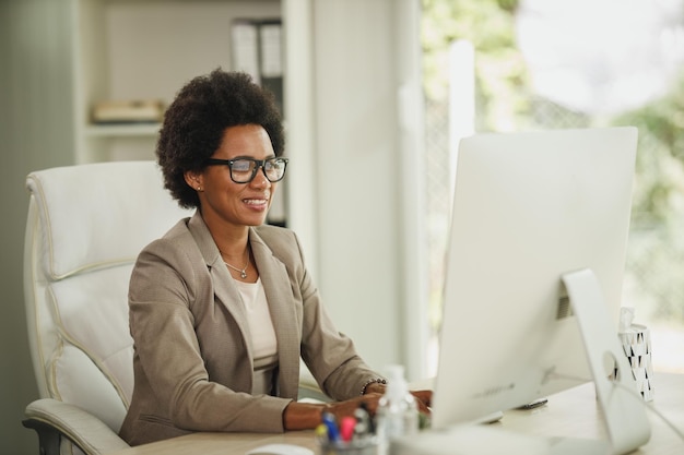 Shot of an African businesswoman sitting alone in her home office and working on computer during COVID-19 pandemic.