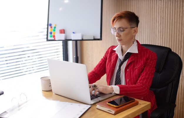 Shot of an attractive mature businesswoman in red suit working on laptop in her office