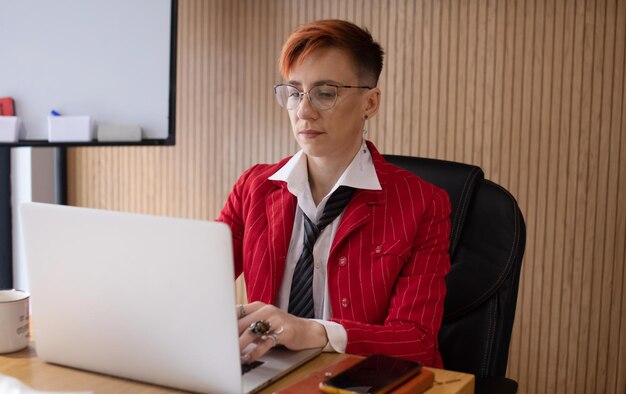 Shot of an attractive mature businesswoman in red suit working on laptop in her workstation