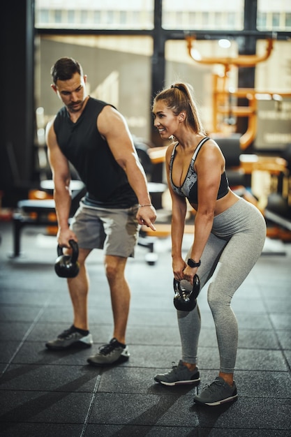 Foto inquadratura di una giovane donna attraente che lavora con un personal trainer in palestra.