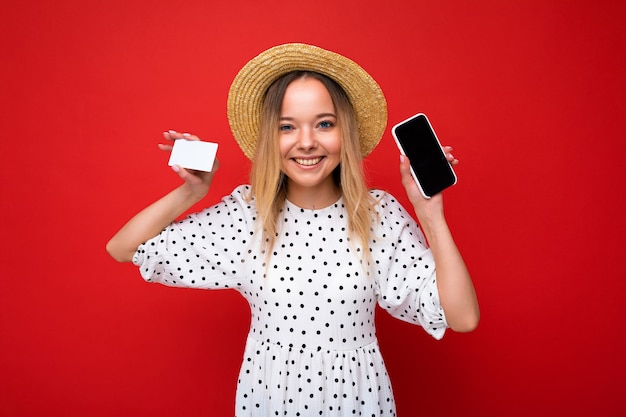 Shot of beautiful happy smiling blonde woman in summer clothes showing smartphone with empty screen