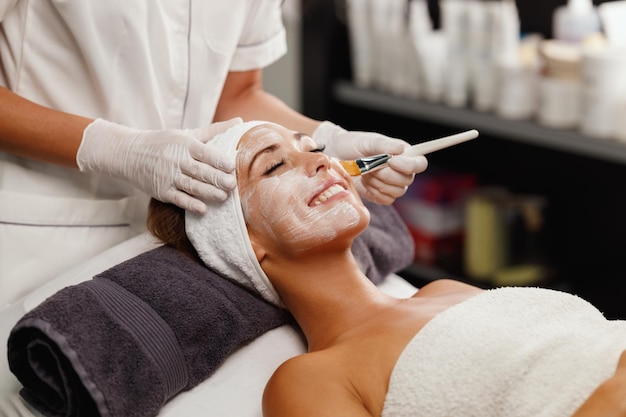 Foto inquadratura di una giovane e bella donna che riceve un trattamento con maschera facciale presso il salone di bellezza.