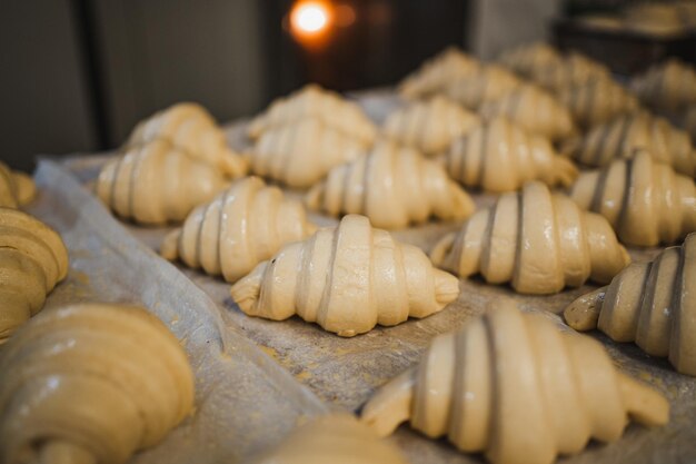 Shot of a bunch of fresh uncooked croissants ready to go to the oven in an artisan bakery