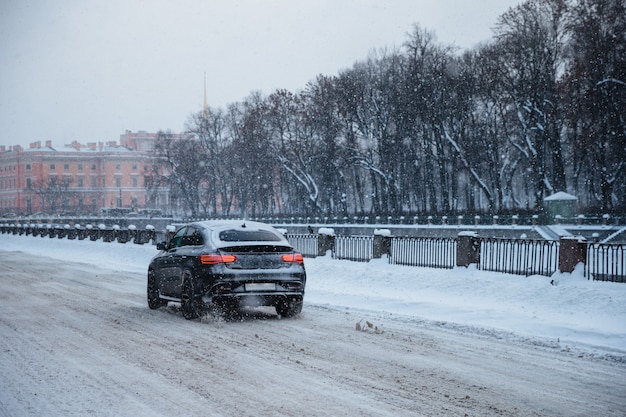 Shot of car covered with white snow, rides slowly as road in slippery and covered with thick white snow