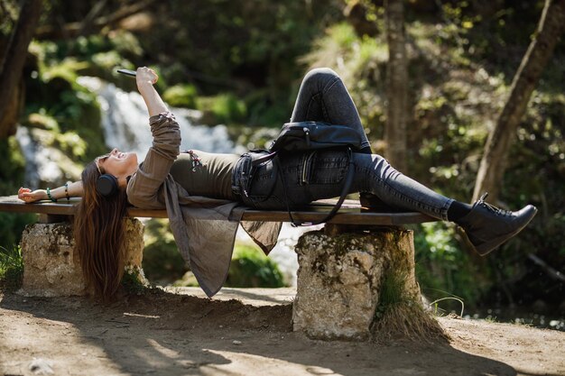 Inquadratura di una giovane donna spensierata che ascolta musica sul suo smartphone mentre si gode la vita all'aria aperta.