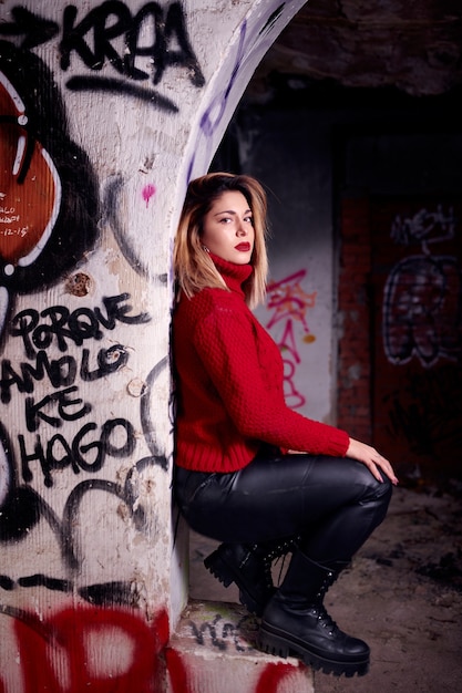 shot of a Caucasian woman wearing a bright top in an abandoned building with graffiti