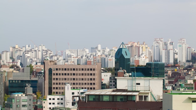 대한민국 서울의 도시 풍경 샷입니다. 고층 건물 및 작업 건설 크레인. 도시 위로 빛나는 태양과 항해하는 구름