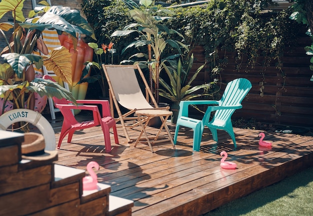 Shot of colored chairs on the wooden floor among the green plants