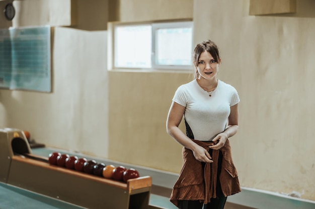 Shot of a cute girl standing at the bowling club and looking at camera.