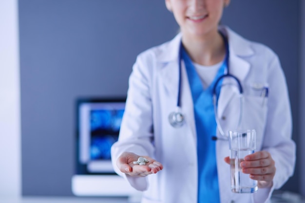 shot of doctor's hands holding pills and glass of water at clinic.