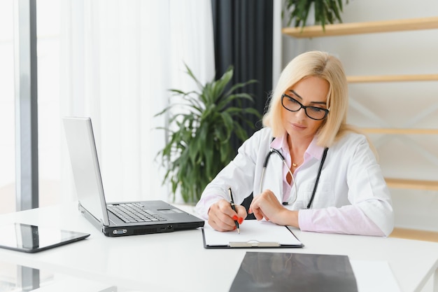 Inquadratura di una dottoressa che lavora mentre è seduta alla scrivania davanti al laptop