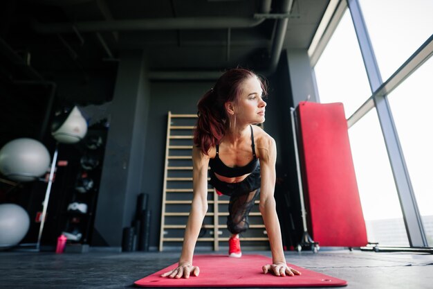 Colpo di donna fitness sulla stuoia di esercizio. atleta femminile sdraiata sulla schiena dopo un allenamento in palestra