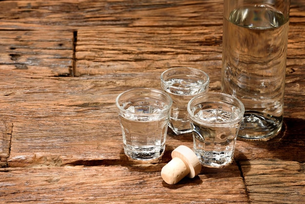 Foto bicchieri da sparo e una bottiglia su un vecchio tavolo di legno con sfondo nero