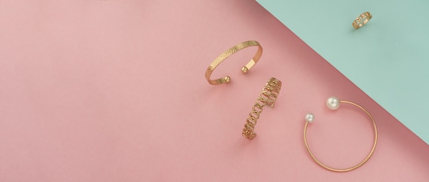 Shot of golden bracelets and ring on pastel colors background with copy space