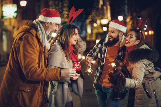 Shot of a group of cheerful young friends having fun with sparklers together outside in the evening.